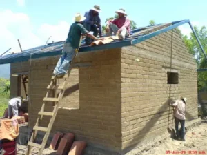 hombres elaborando techo sobre una casa ecologica