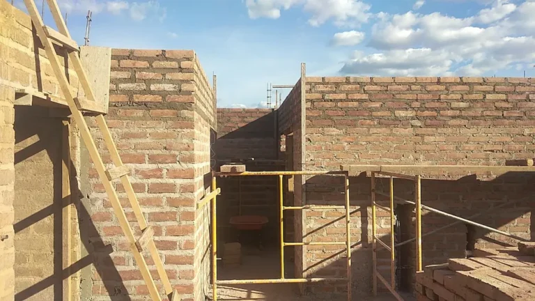 Bloques de tierra comprimida de Ecomobilia apilados junto a la pared en construcción