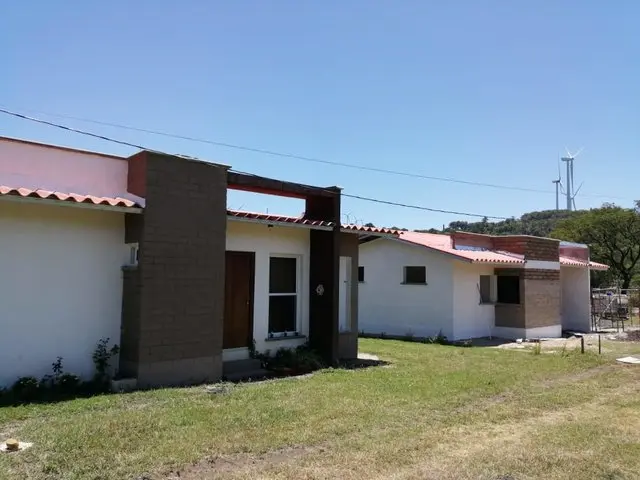 Fachada de una casa ecológica de Ecomobilia con cubierta de teja, alero y paredes claras