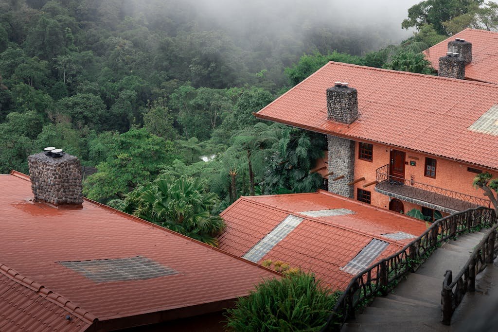 Charming red-roofed villas nestled in a misty lush forest setting, offering serenity and natural beauty.