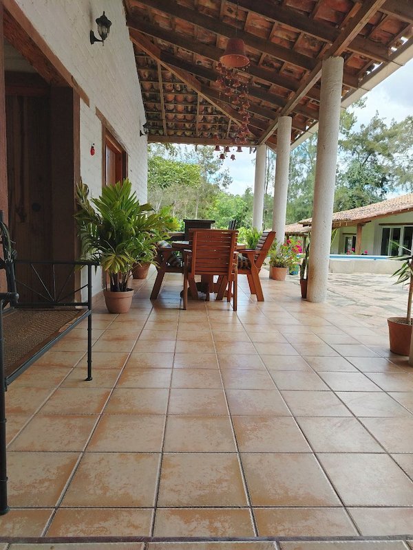 Terraza cubierta de una casa ecológica de Ecomobilia, con piso de barro cocido, techo de teja y mesa de madera
