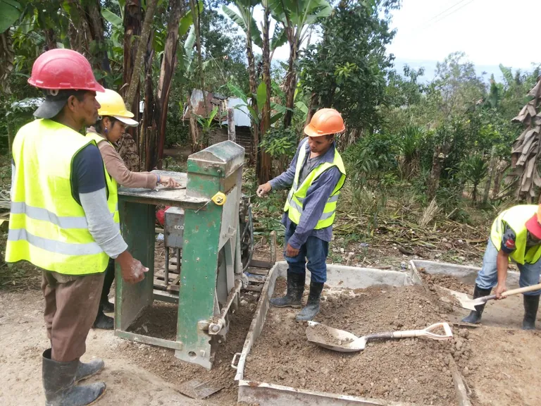 Cuadrilla elaborando bloques de ADB-Concreto con la bloquera en la obra de la escuela en El Porvenir, La Paz