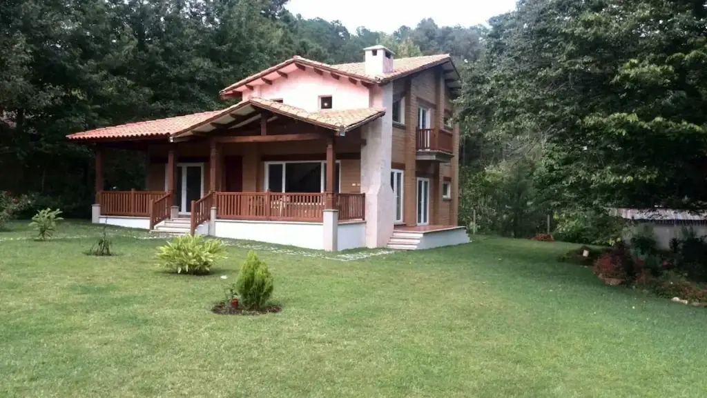 Casa de tierra de dos niveles construida en colaboración con Ecomobilia en Honduras, con balcón de madera y cubierta de teja