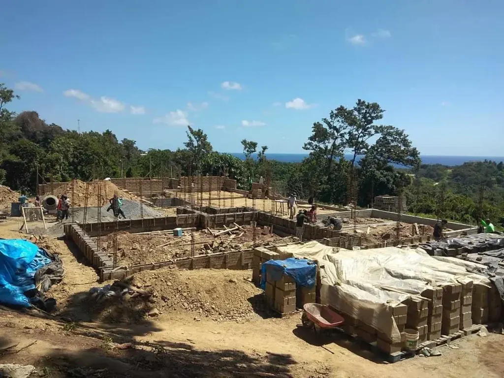 Paredes de ADB-Concreto en construcción, con los bloques apilados y el terreno alrededor