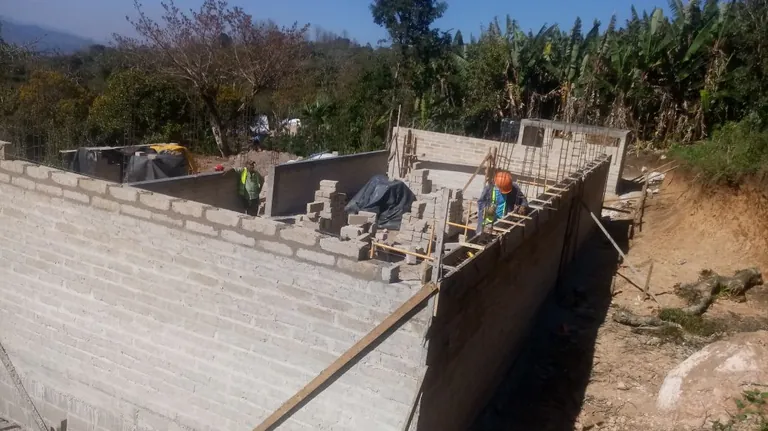 Muros de ADB-Concreto de la escuela en construcción con trabajadores sobre la solera, en El Porvenir, La Paz