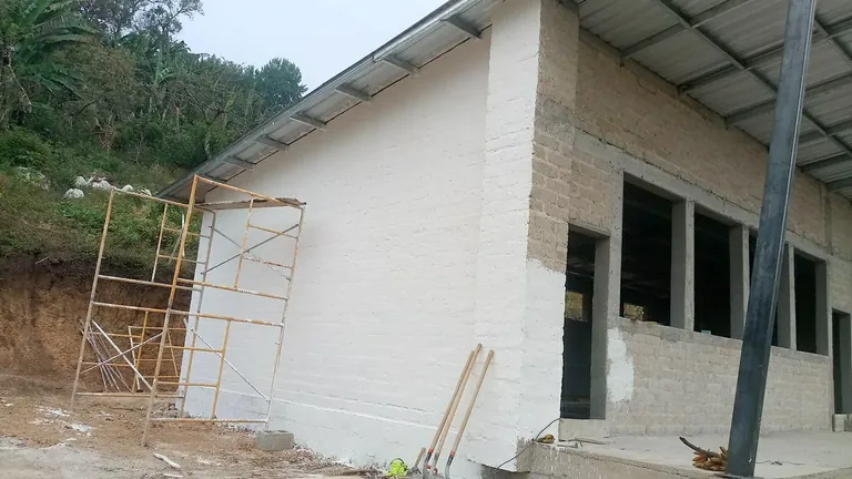 Fachada terminada de la escuela con muros de ADB-Concreto revocados en El Porvenir, La Paz